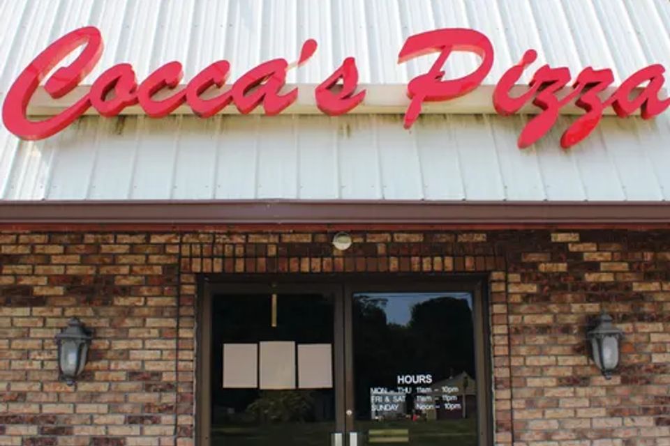 Cocca’s Pizza Cortland, Ohio storefront featuring a brick exterior, glass double-door entrance, and large red Cocca’s Pizza sign above the entrance.