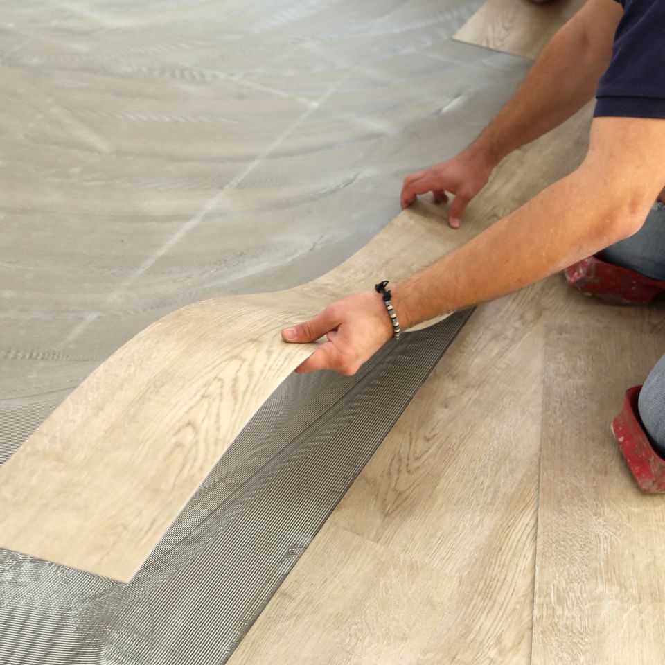 Installer pressing a luxury vinyl plank into place during a vinyl flooring install