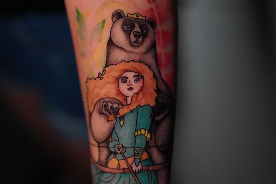 Image of a tattoo of a woman and bear in colorful ink