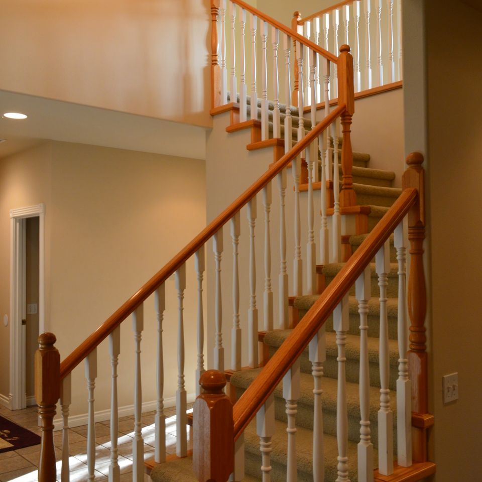 Two story entry stairway with wood railing and painted spindles in a finished custom home