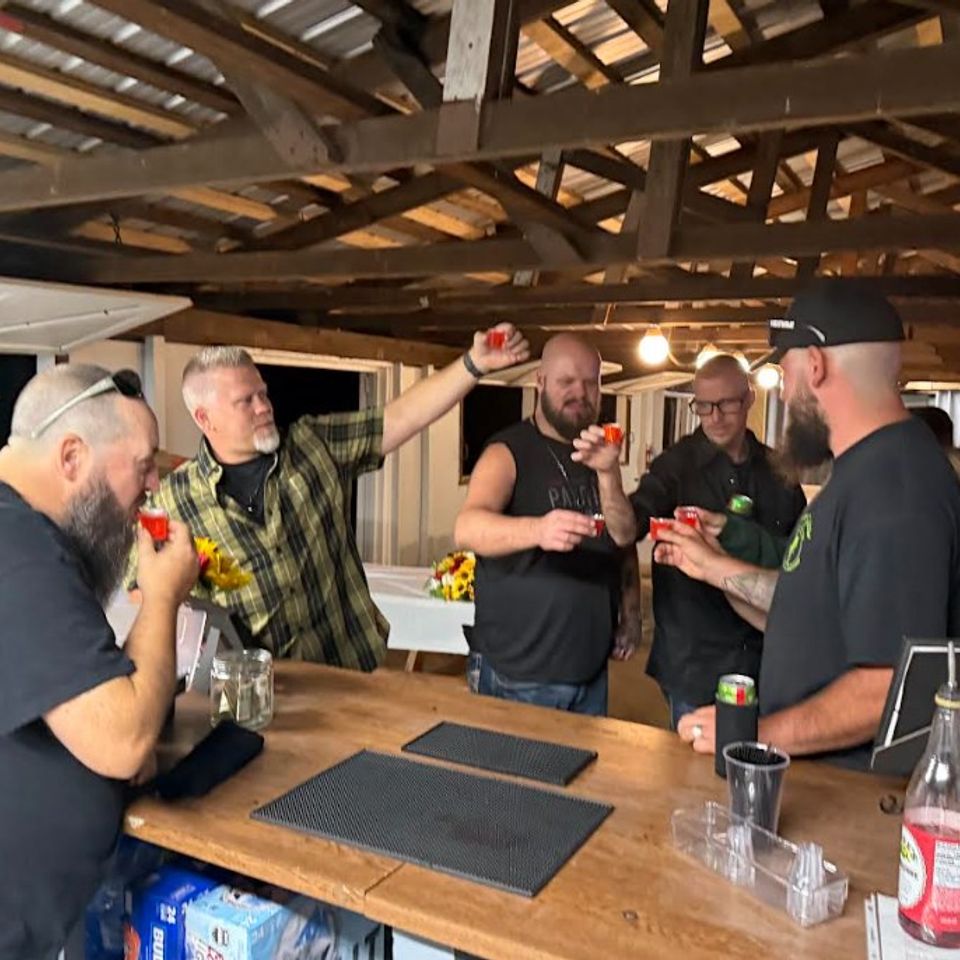 Men taking shots together at the full bar setup during the wedding reception