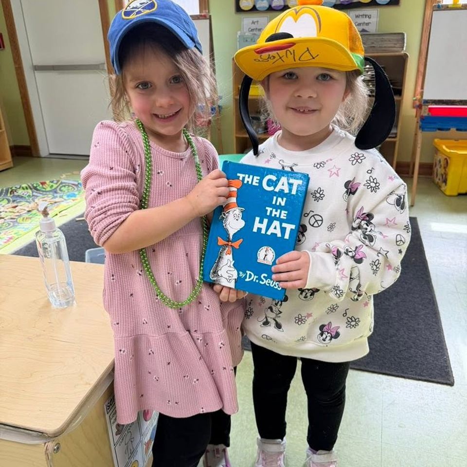 Two Pre-k 4 girls holding a Cat in the Hat book