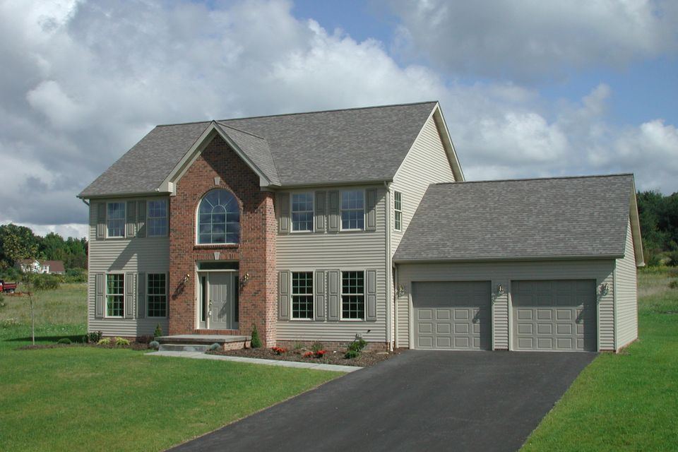 Two-story energy-performance home with a brick and siding exterior, attached three-car garage, and professionally landscaped front yard.
