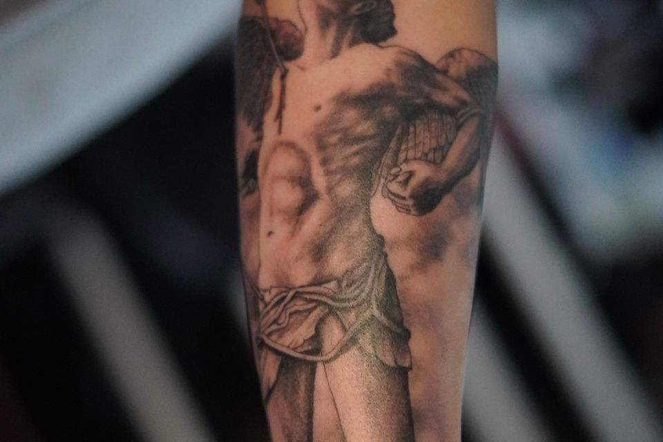 Image of a tattoo of a man who appears to be ascending or floating with an arrow in his right shoulder, dressed only in a loin cloth, appears to be a biblical reference