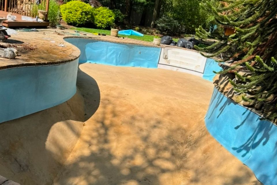 Empty inground pool with bare sand floor prepped for liner replacement in Long Island NY