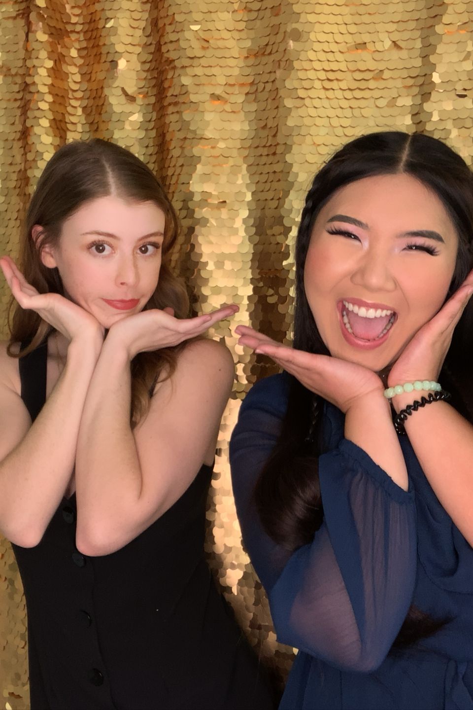 Friends smiling and striking a fun pose in front of a shimmering gold background.