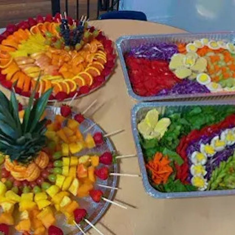 African catering spread with layered vegetable salad trays and pineapple fruit platter for a Los Angeles CA event