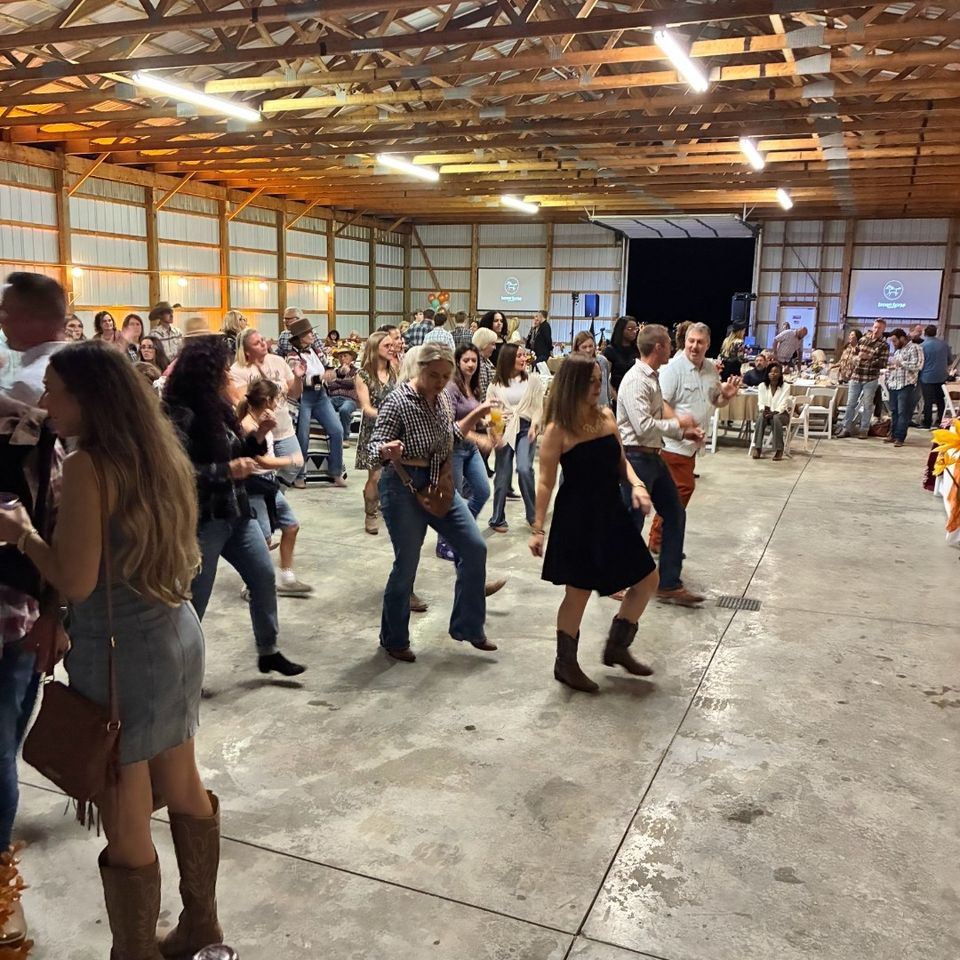 Guests line dancing together at a Barnyard Bash event