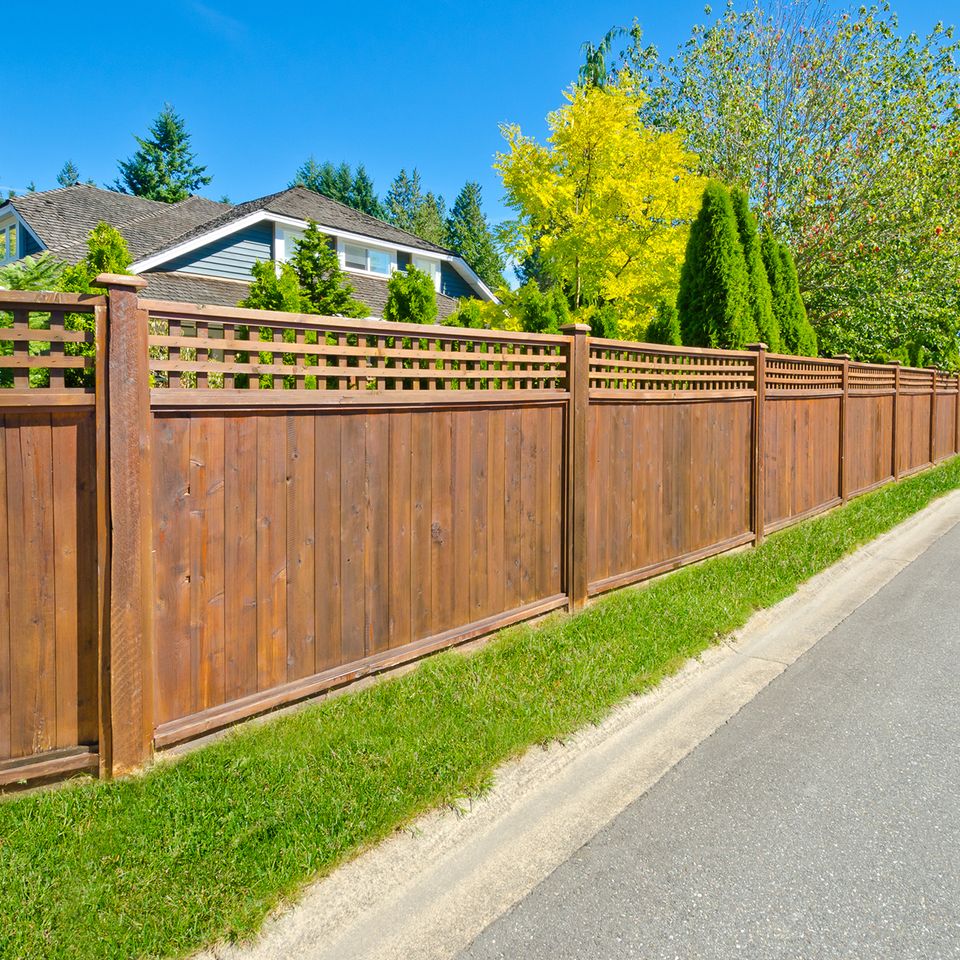 Professional wood privacy fence with lattice top installed along residential property line