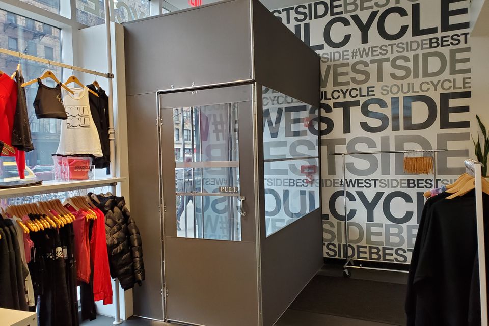 Brushed aluminum vestibule with a glazed door built inside a retail store entrance, photographed from the sales floor