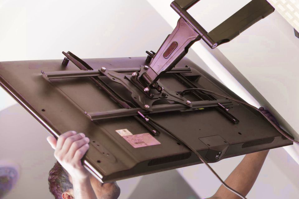 Technician mounting a TV on a wall, ensuring secure installation.
