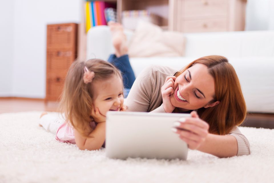 Cute little girl with mom using digital tablet home