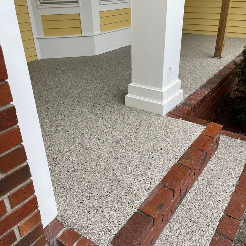 Front porch and steps finished with Quartz Carpet flooring around white columns and brick accents.