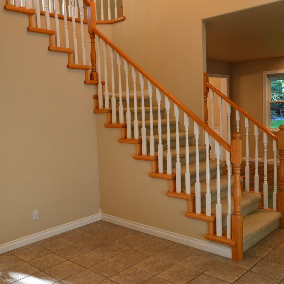 Carpeted staircase with stained oak handrail and white turned balusters in a custom home