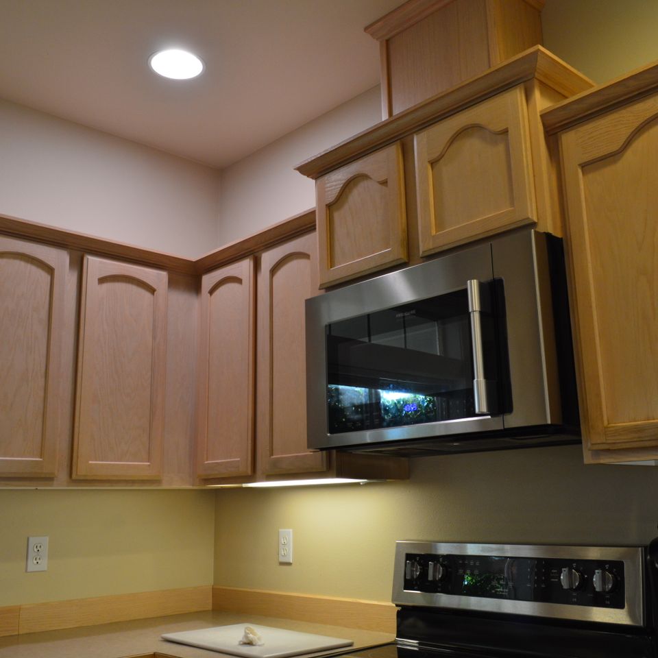 Kitchen with maple cabinets, stainless microwave, and under cabinet lighting in a custom home build