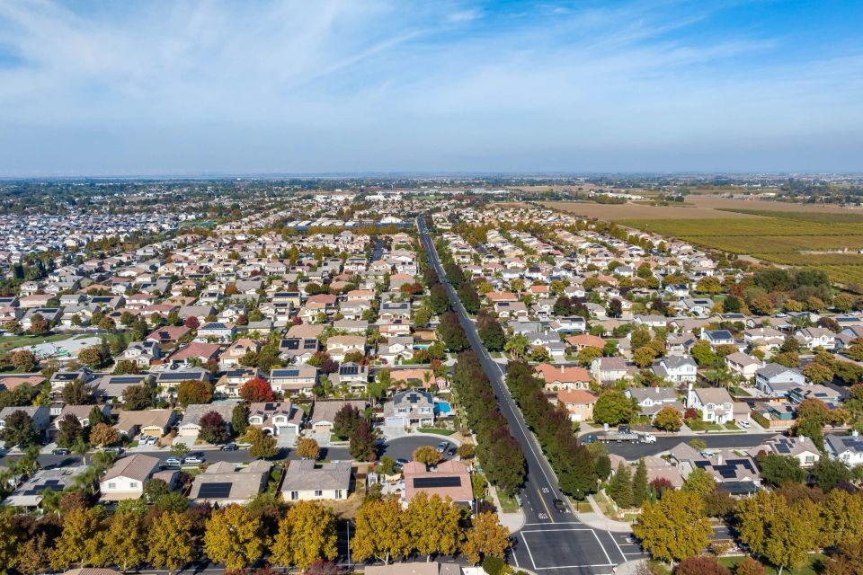 Aerial drone view of Newcastle, California, showing the rugged ridge-line estates, historic fruit orchards, and the dense oak and pine forest canopy along Interstate 80.