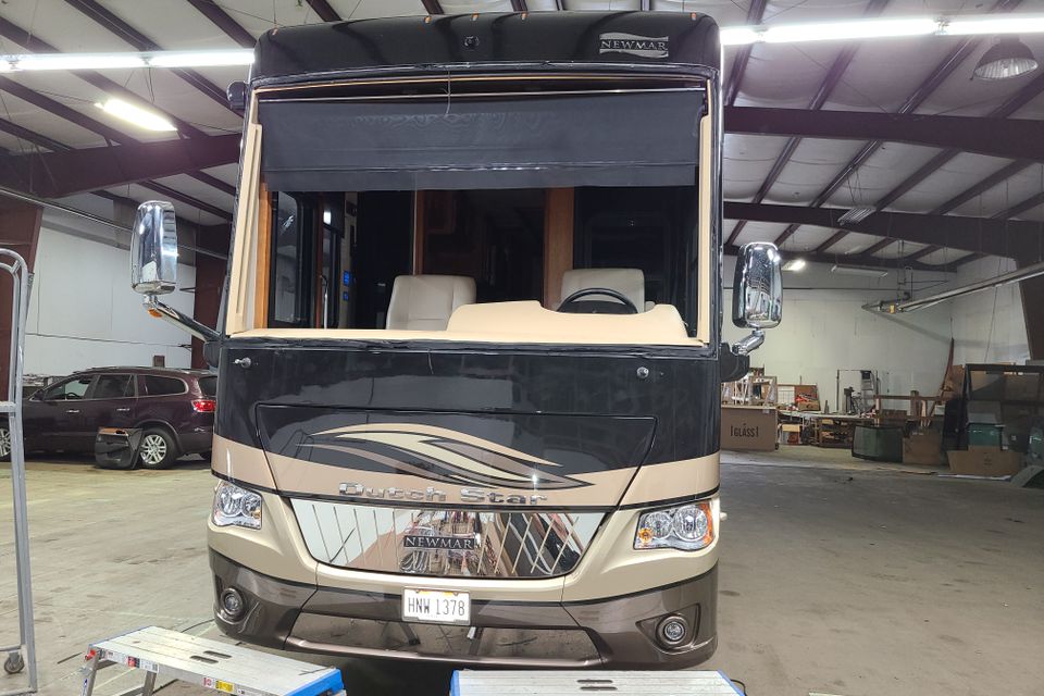 Motorhome inside an auto glass shop receiving a professional RV windshield replacement.