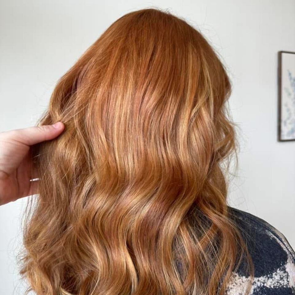 Long wavy copper hair with golden blonde highlights after color and styling in Columbiana AL