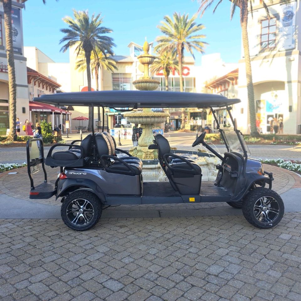 Six-passenger street-legal golf cart rental parked by a fountain at an outdoor shopping plaza in Destin FL