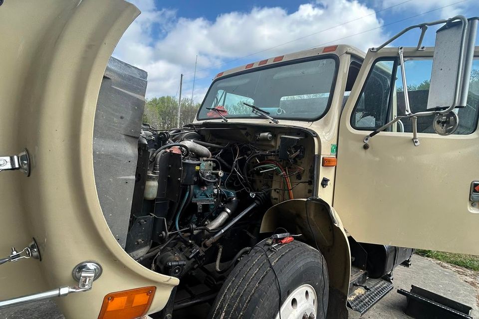 Tan International medium-duty truck with hood tilted open for diesel engine repair in Arab Alabama