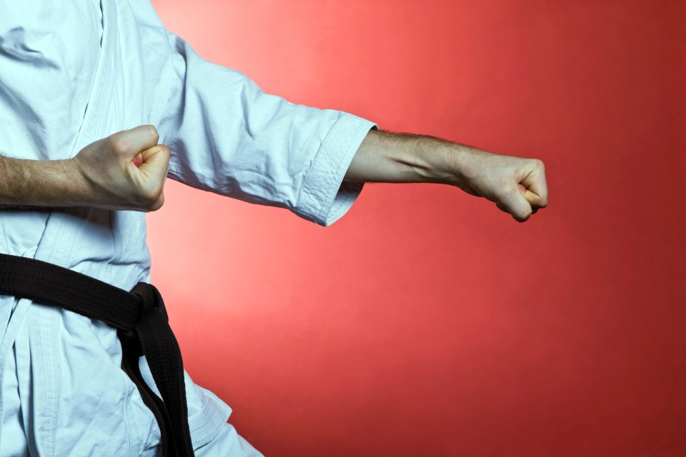 A karate black belt practicing a forward stance punch during a kata