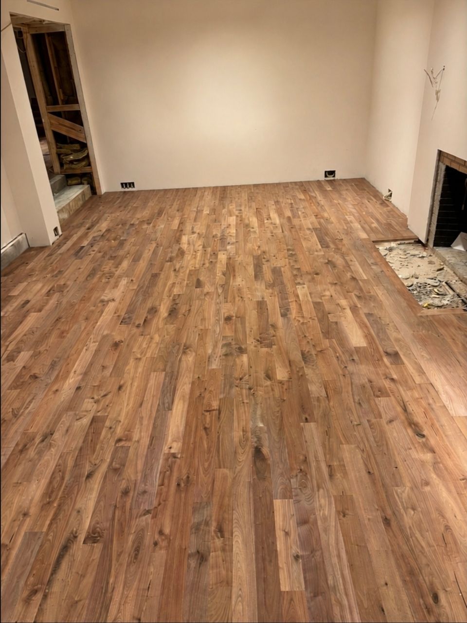 Rich brown hardwood flooring installed in a living room beside an open fireplace hearth in Northeast Ohio