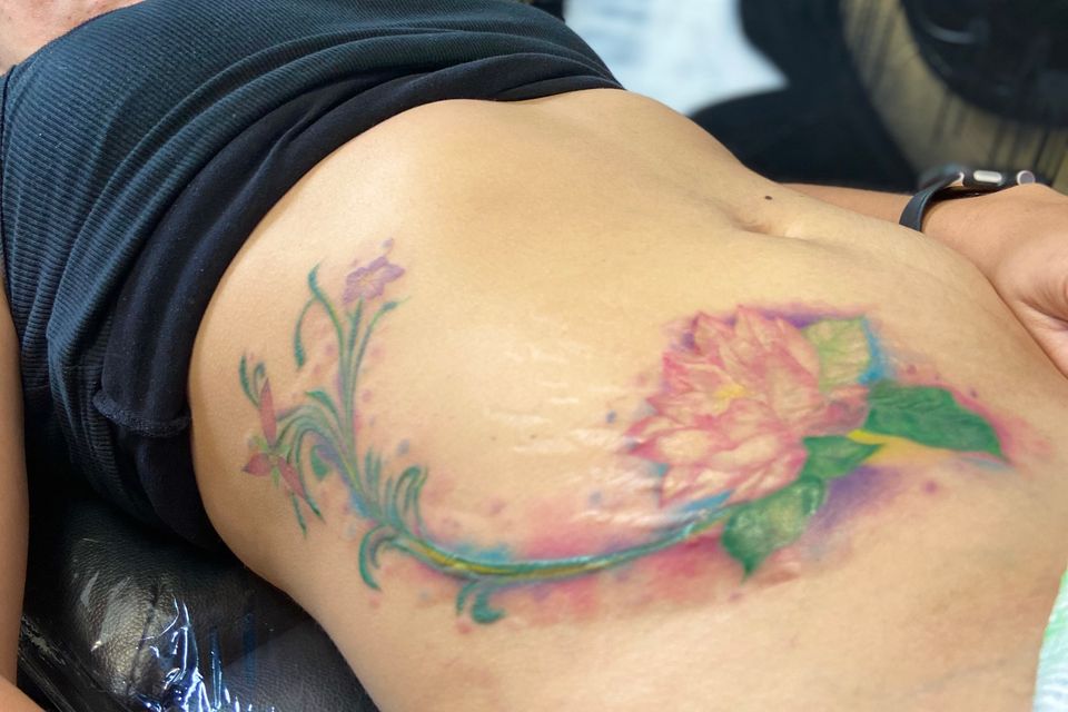 Image of a very colorful flower and leaf tattoo that appears to be covering up stretch marks