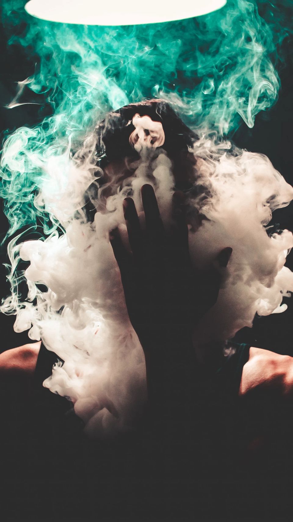 Silhouette of person creating smoke cloud with overhead light