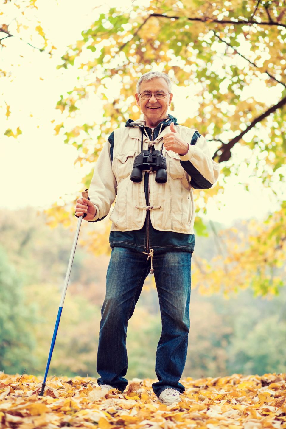 Happy senior man hiking in forest in autumn.