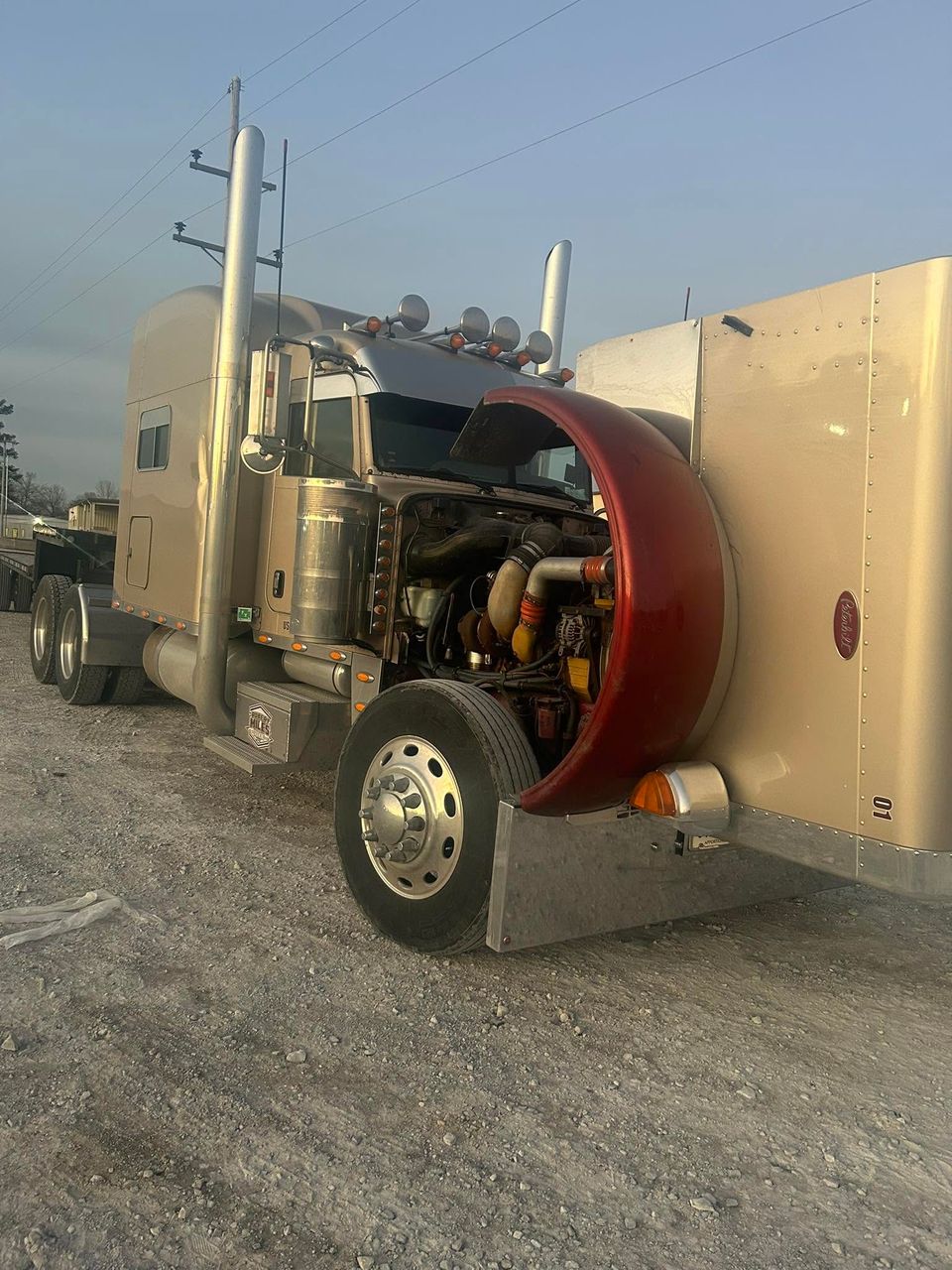 Tan Peterbilt semi-truck with hood tilted open for diesel engine service in Arab Alabama