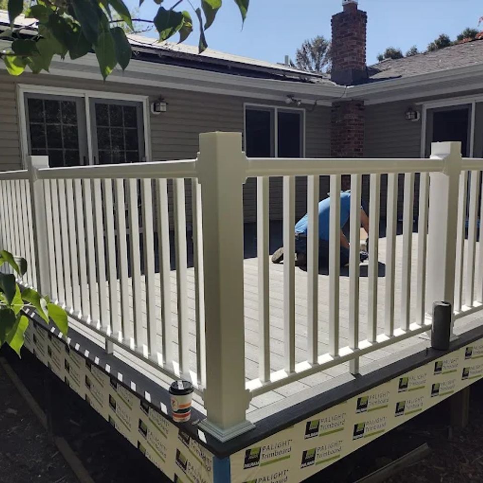 A beautiful deck in the sun with a worker on it adding finishing touches done by Taurus Contracting