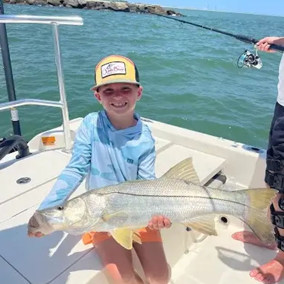 Boy holding a large fish on a boat at the beach