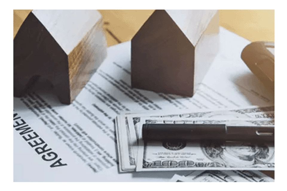 Money and agreement documents on desk with small model houses