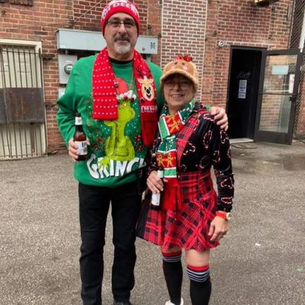 Two attendees posing together outdoors in colorful Christmas-themed clothing and accessories.
