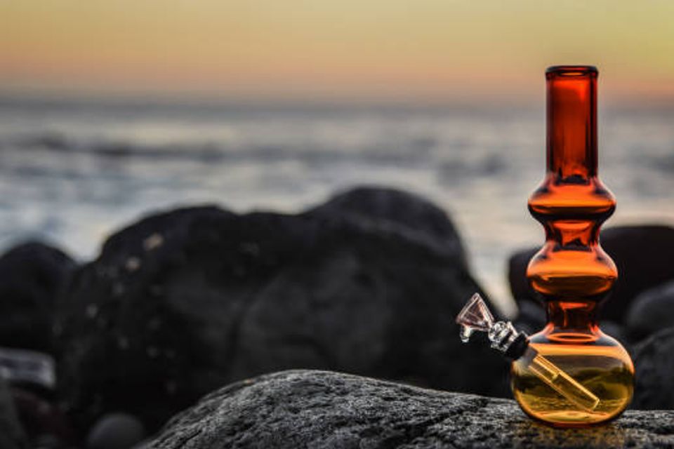 Bong resting on a rocky beach during a serene sunset.