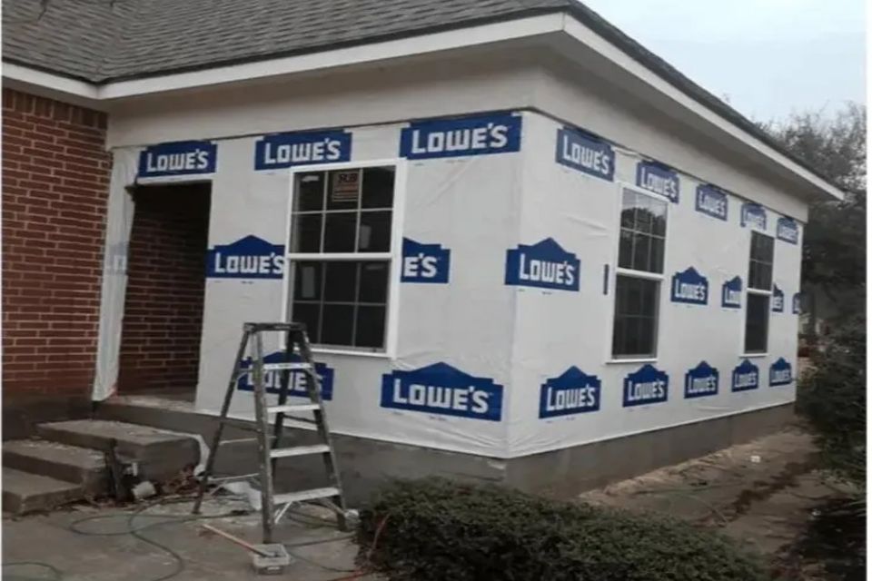 Enclosed porch addition under construction with house wrap and new windows