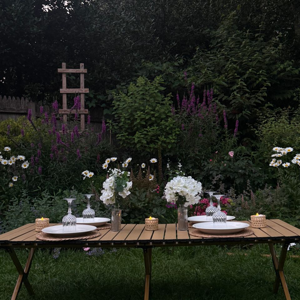 Garden table styling with hydrangeas, candles, and glassware set at dusk in a Hamptons NY backyard