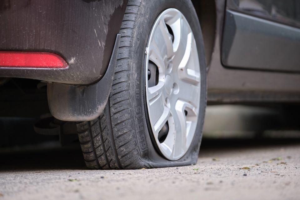 Car with punctured flat tire parked on roadside