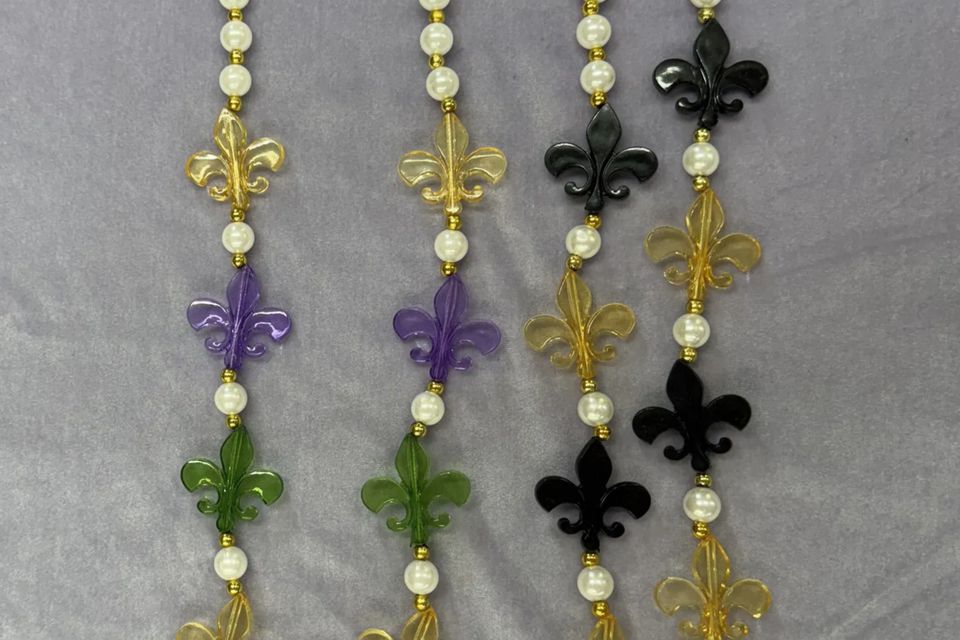 Fleur-de-lis bead necklaces — one in purple, green, and gold, and another in black and gold.