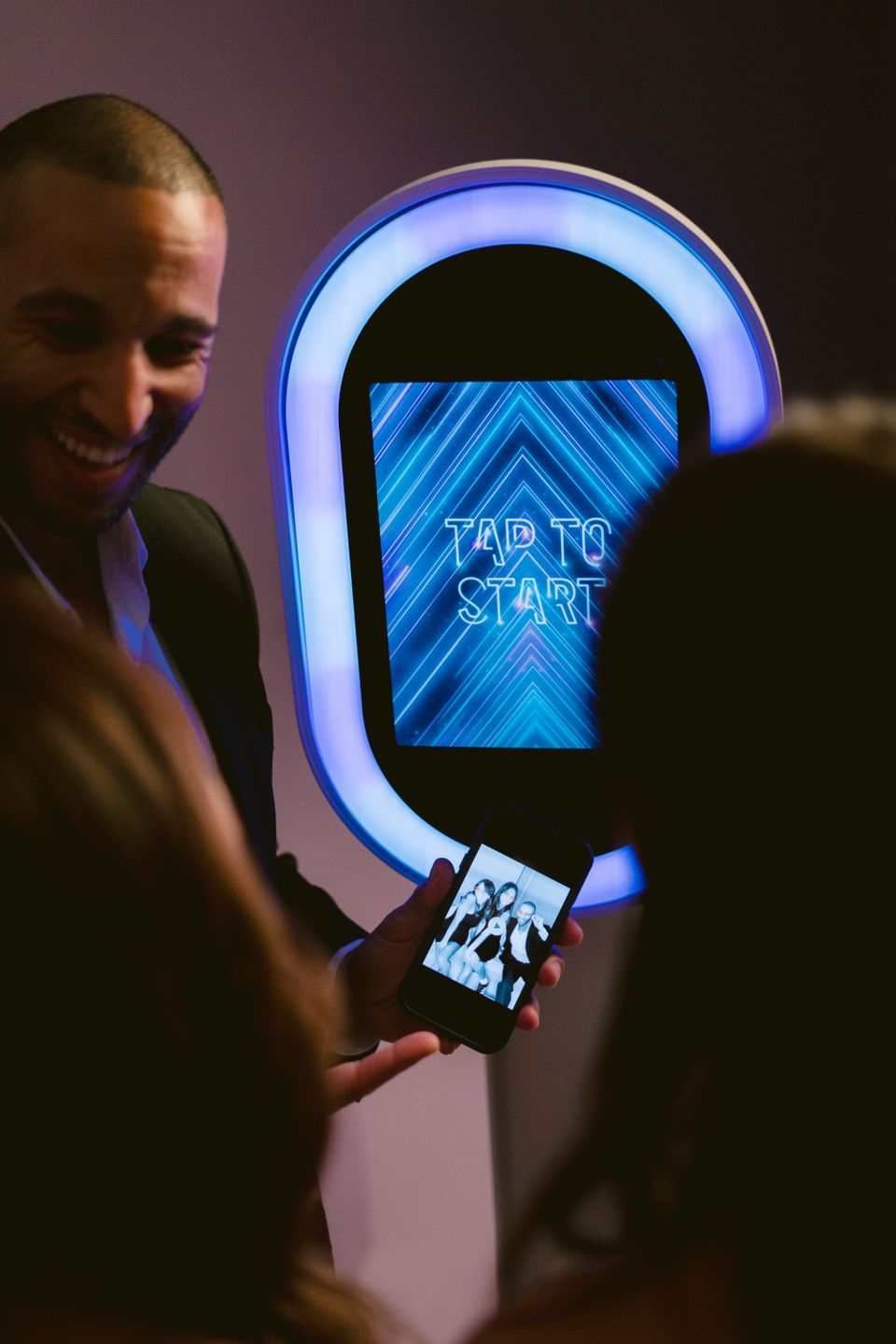 Man holding phone showing a photo taken at a photo booth.