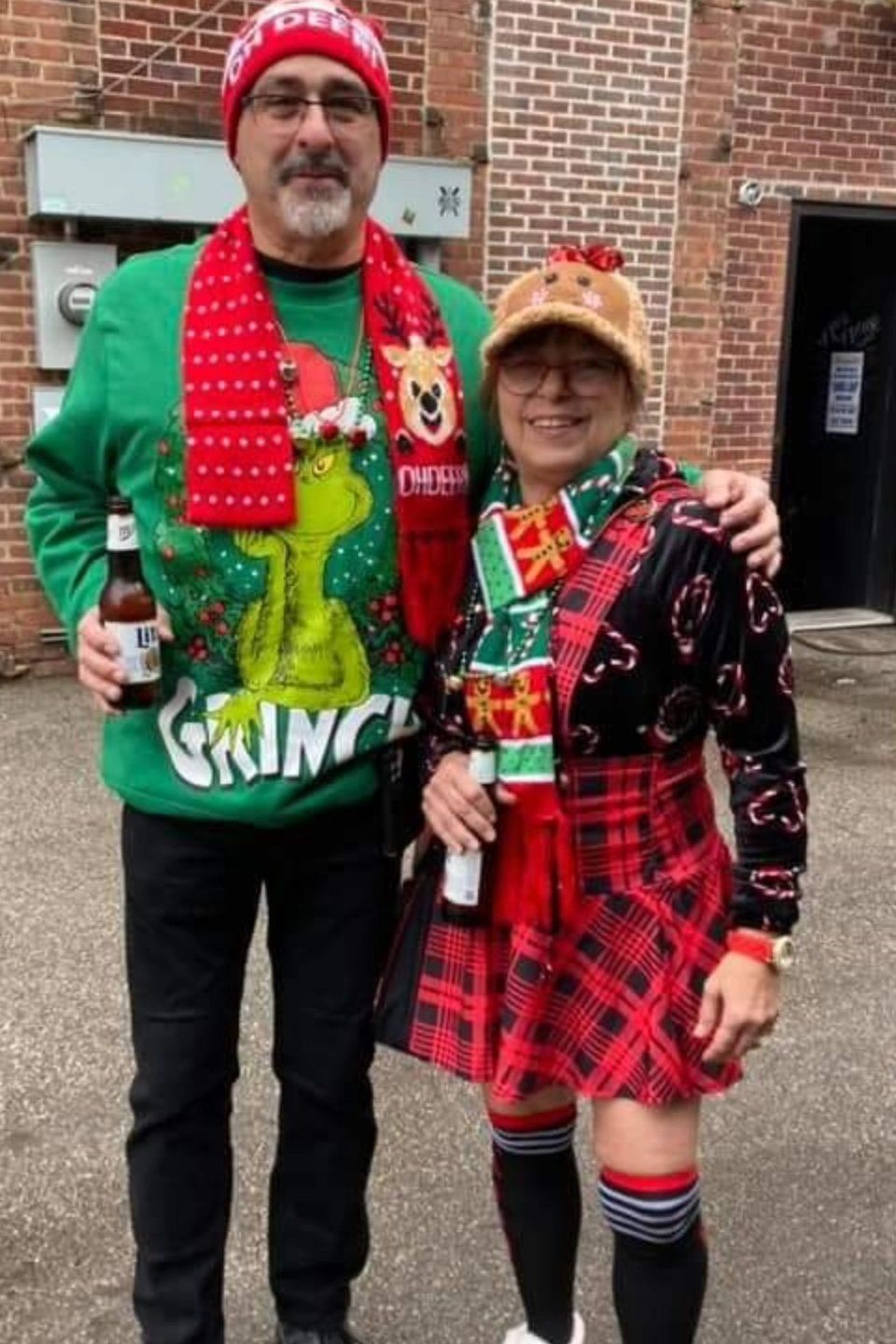 Two attendees posing together outdoors in colorful Christmas-themed clothing and accessories.