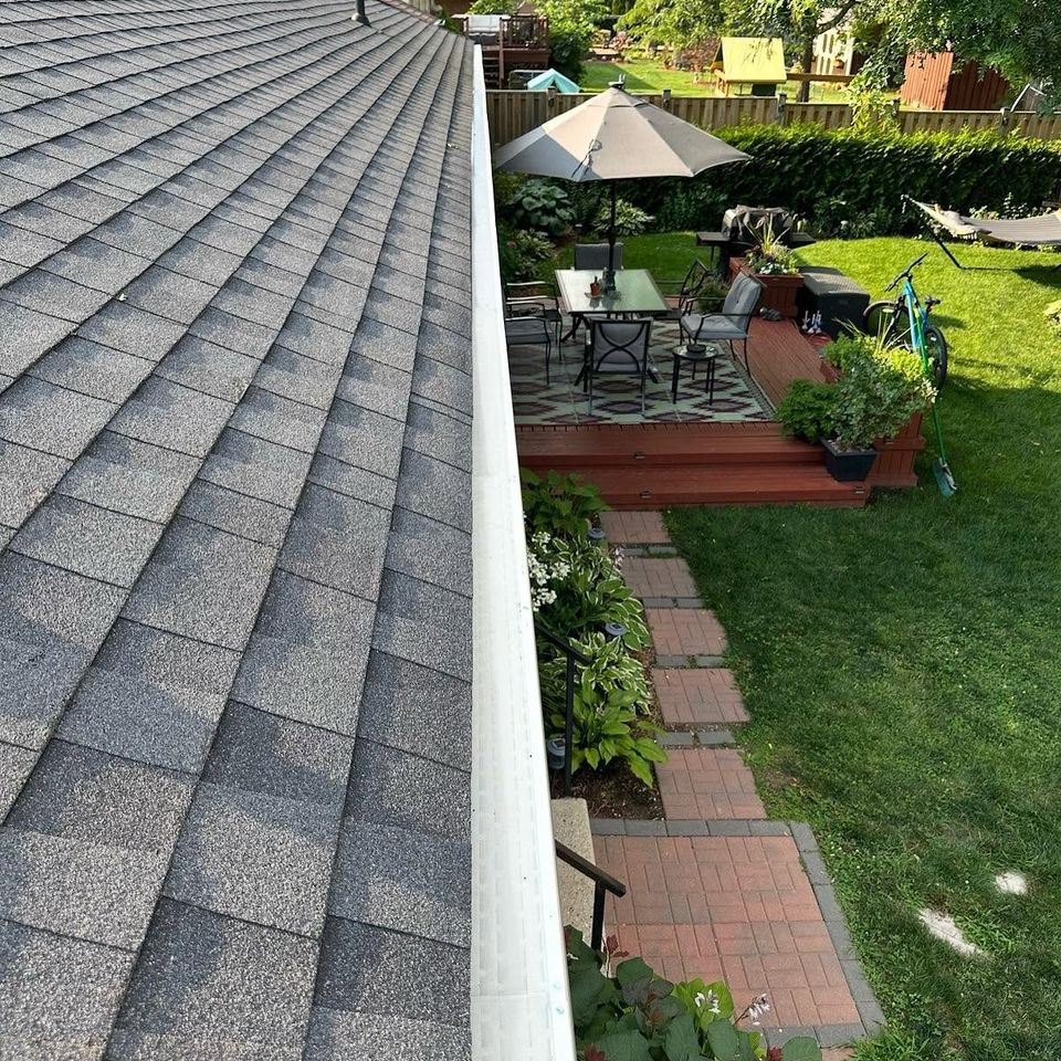 White gutter guard installed along asphalt shingle roof edge overlooking backyard patio in Tillsonburg ON
