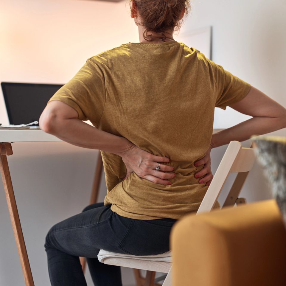 A woman working on a laptop at home and having problems with hips and lower back