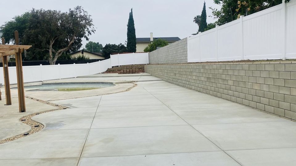 Residential retaining wall construction with large concrete patio and backyard improvement project