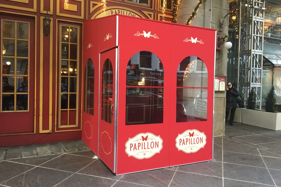 Red painted vestibule with arched windows and branded oval logo panels at an ornate building entrance