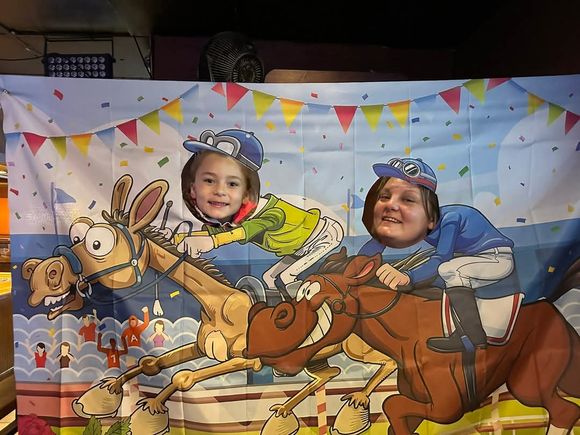 Two guests posing as jockeys in a Kentucky Derby-themed photo booth at JR's 2025 event.