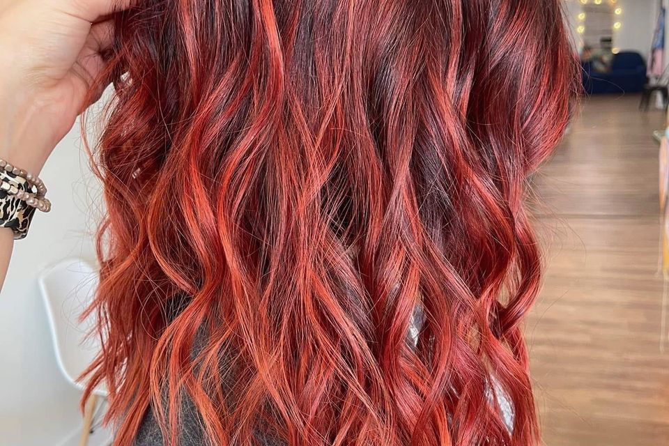 Medium wavy hair with bright red highlights over dark base after color service in Columbiana AL