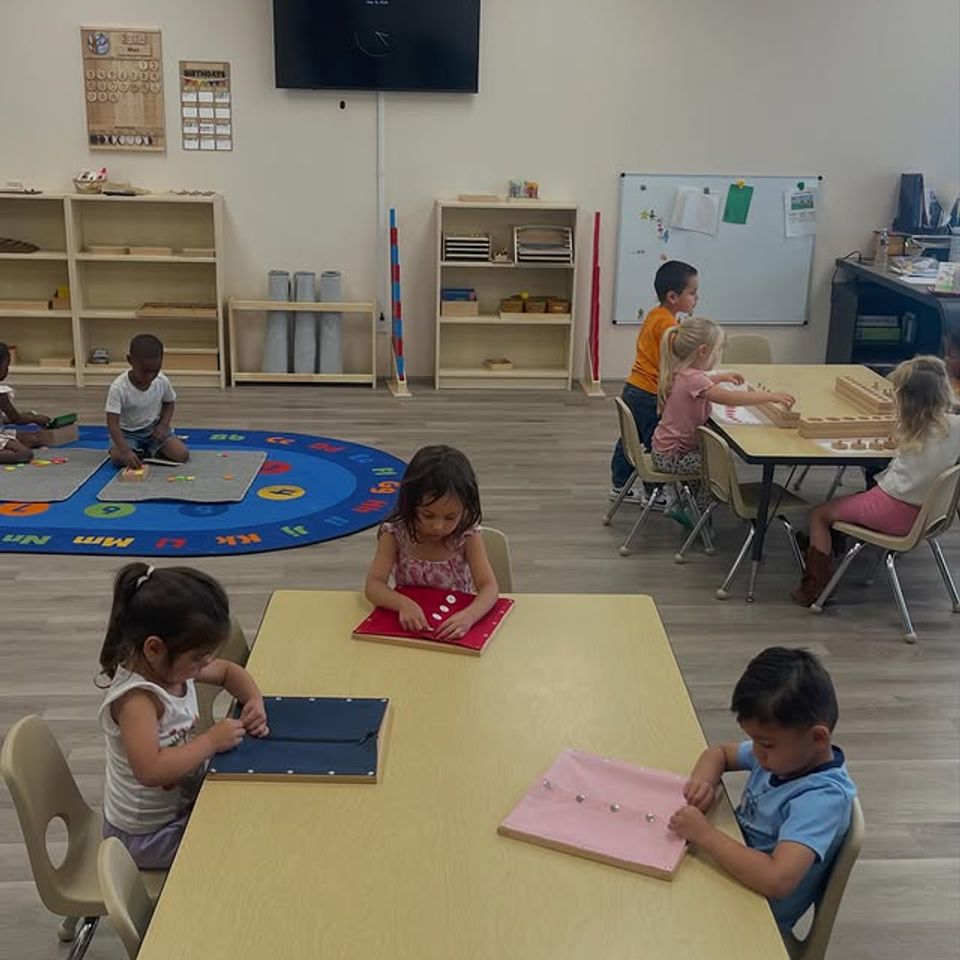 Montessori classroom full of preschoolers working at tables and on the rug during morning work time in Palmdale CA