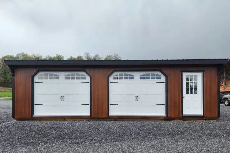 Stained wood double-wide garage with two white carriage doors in East Tennessee