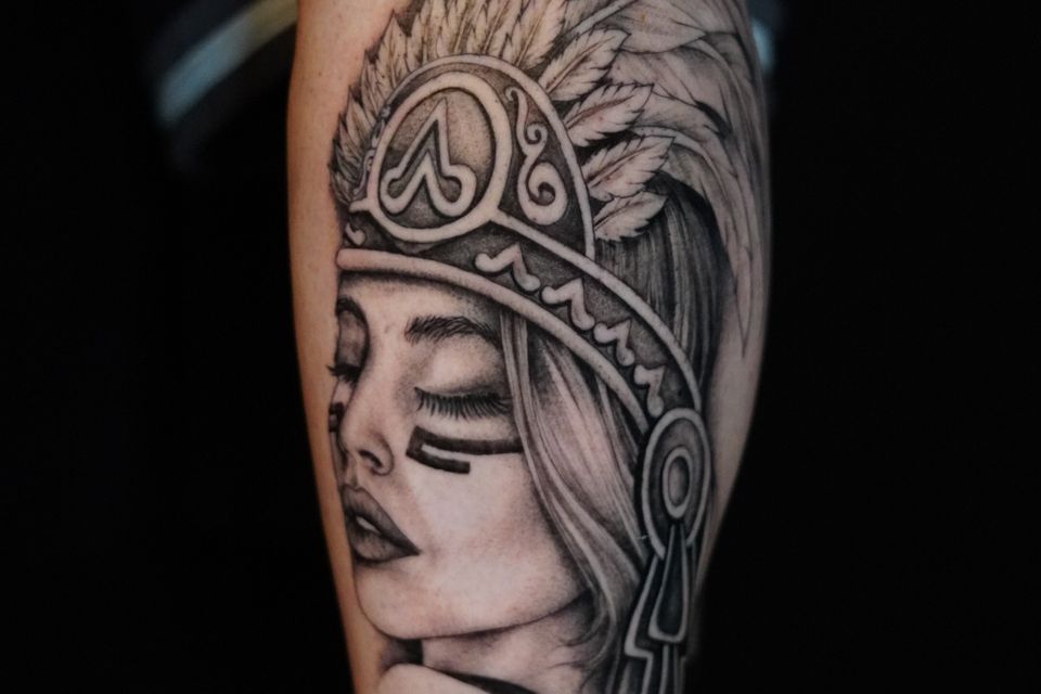 Image of a Native American woman wearing a very detailed feather headress